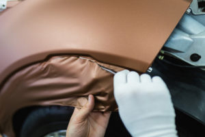 Technician applying bronze color wrap to vehicle